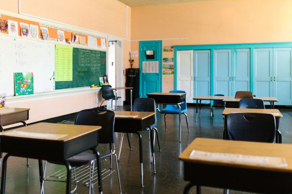Bright empty classroom with desks, blackboard and educational materials
