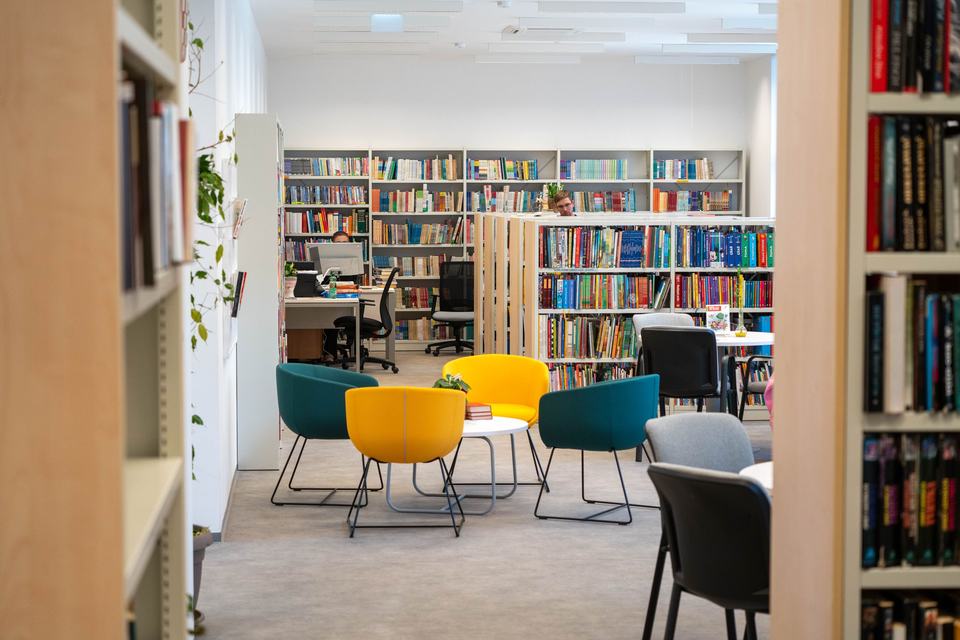 Bright library with bookshelves, tables and colorful chairs